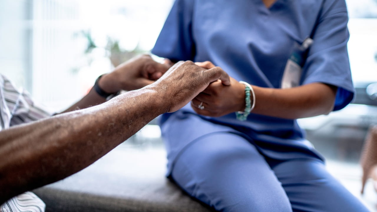 A nurse holding a patient's hands